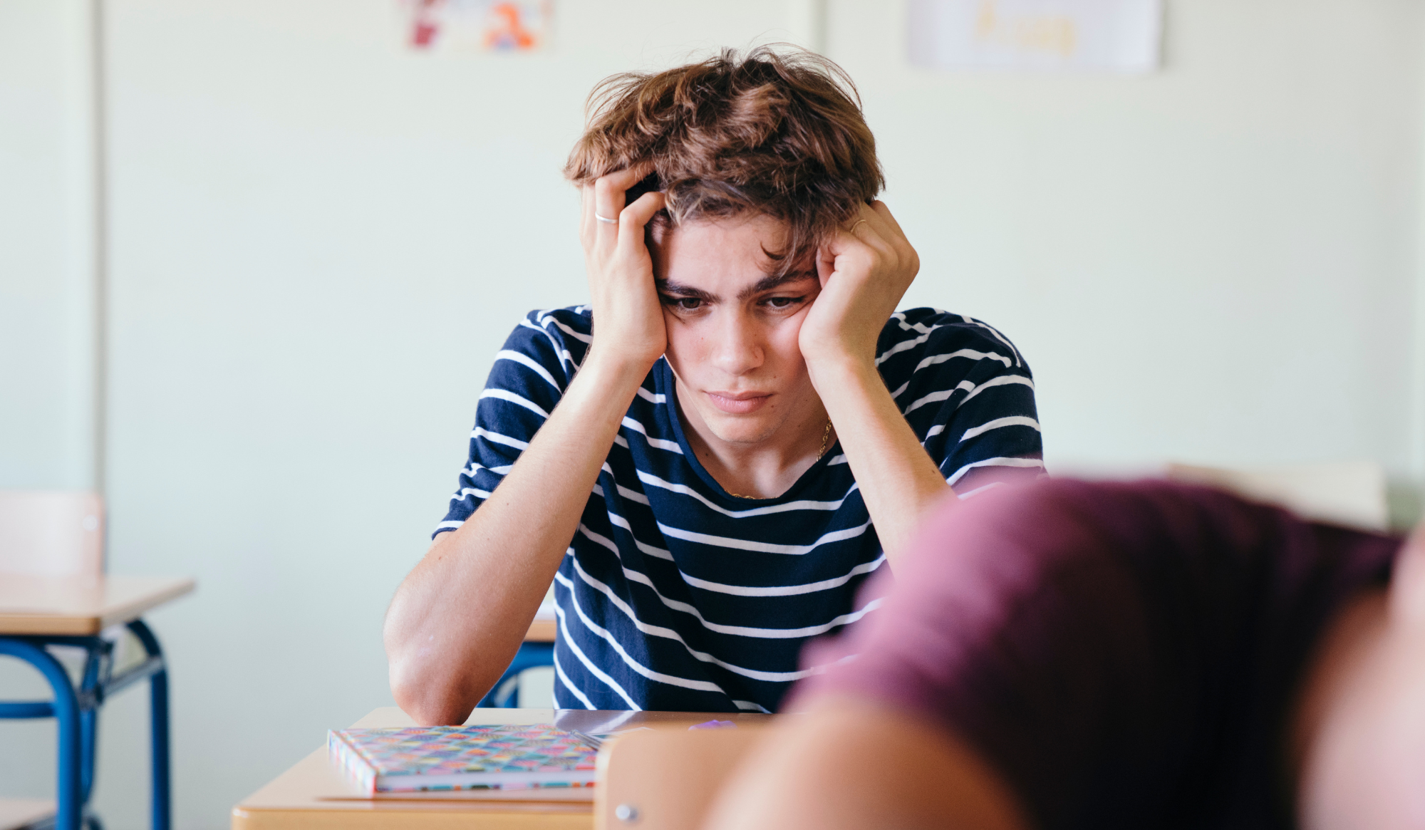 teen student holding his head in his hands