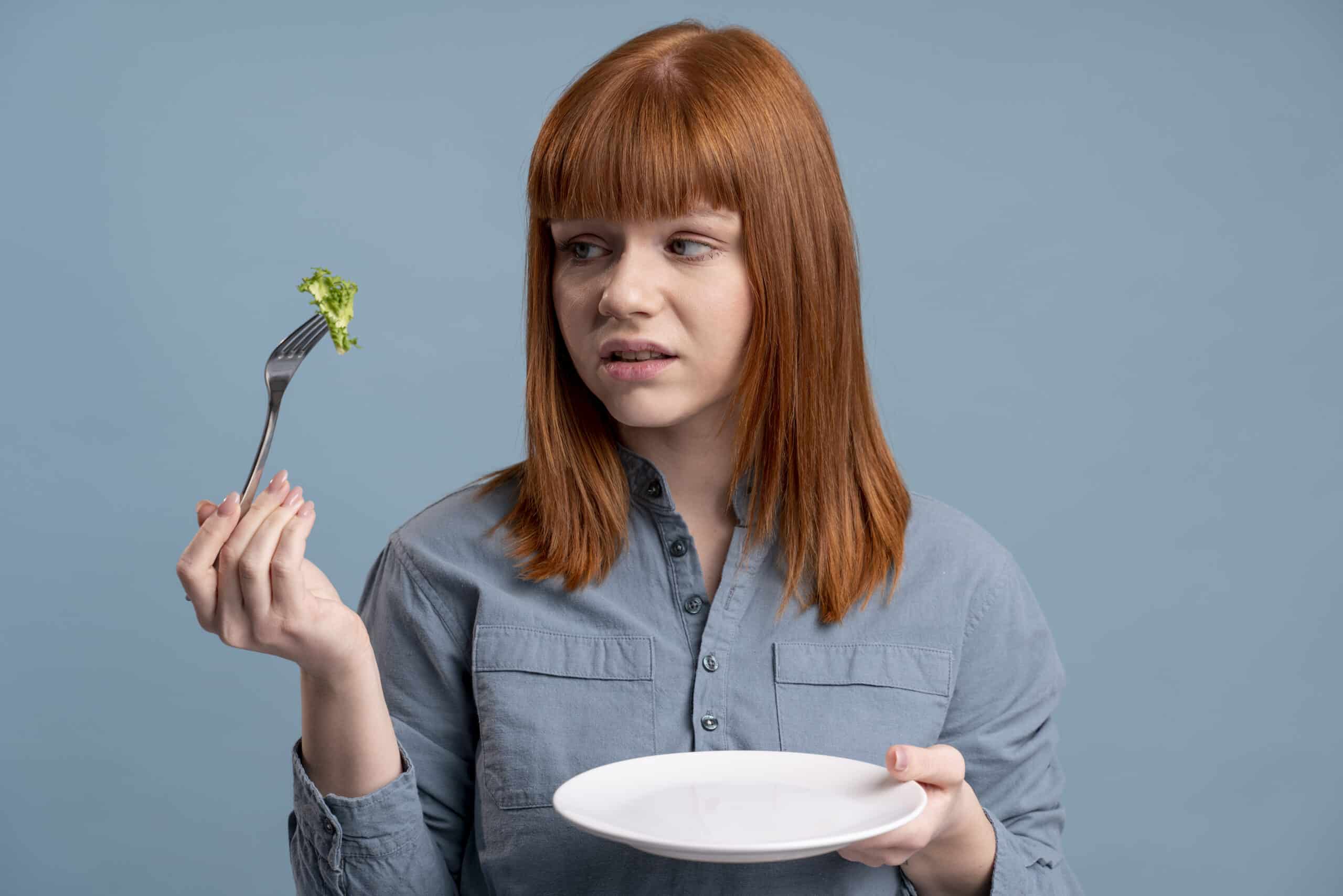 Young woman hesitantly looking at her food.