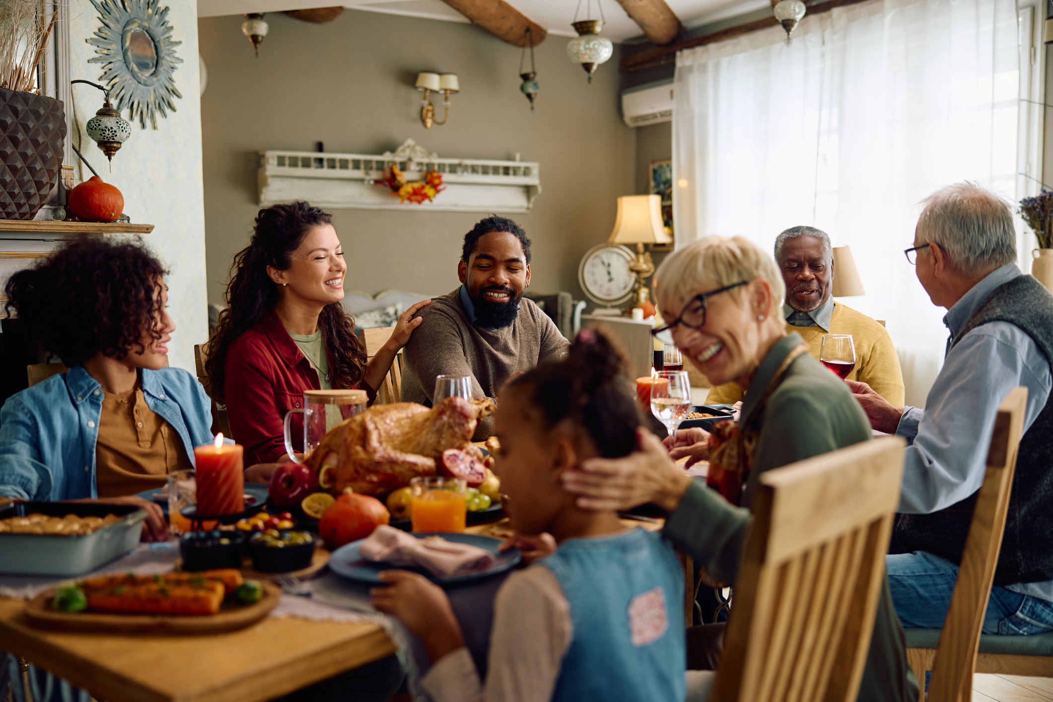 A multigenerational family sharing conversation around a Thanksgiving dinner table.